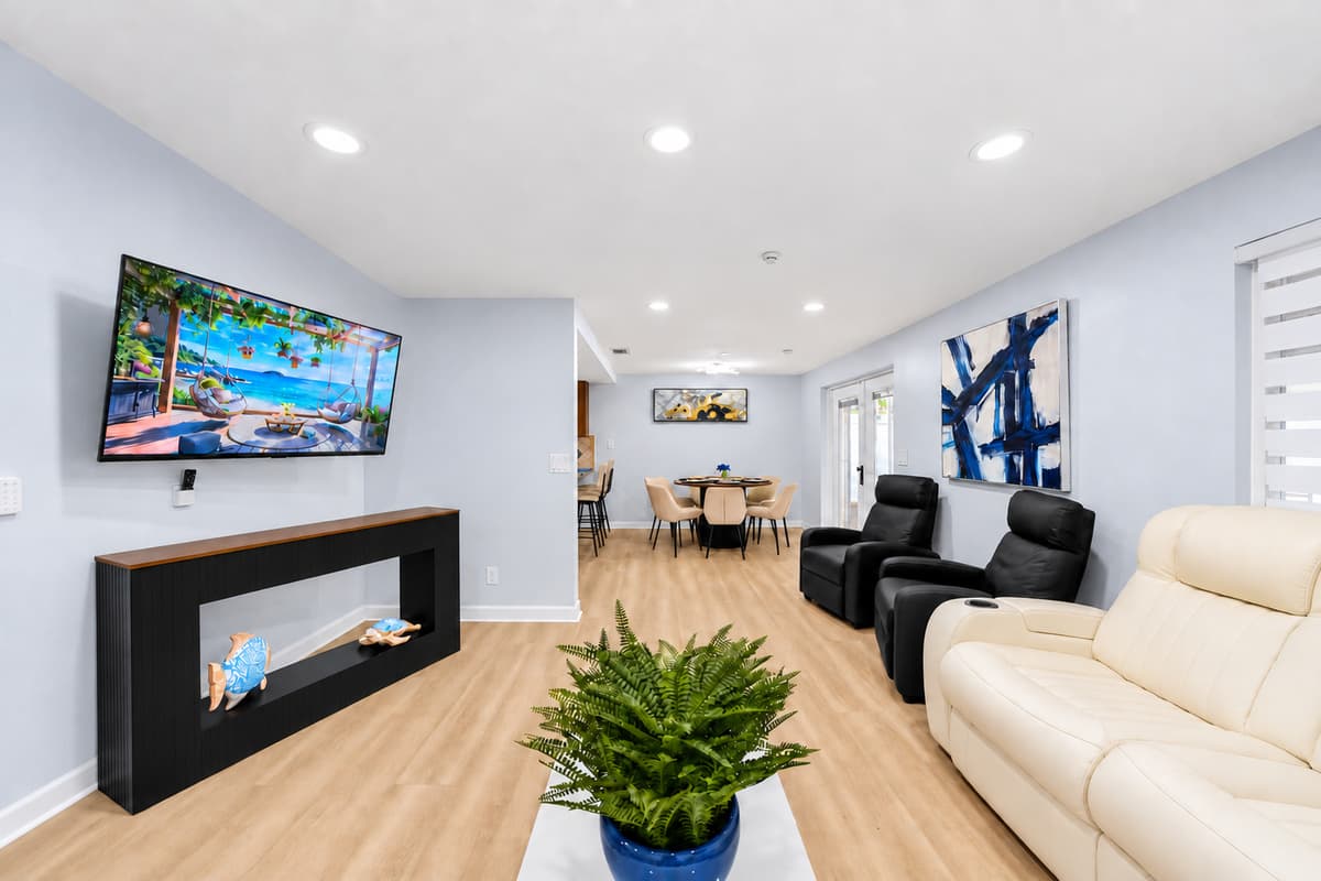Modern living room with large flat-screen TV, comfortable reclining seating, and a stylish fireplace feature wall.