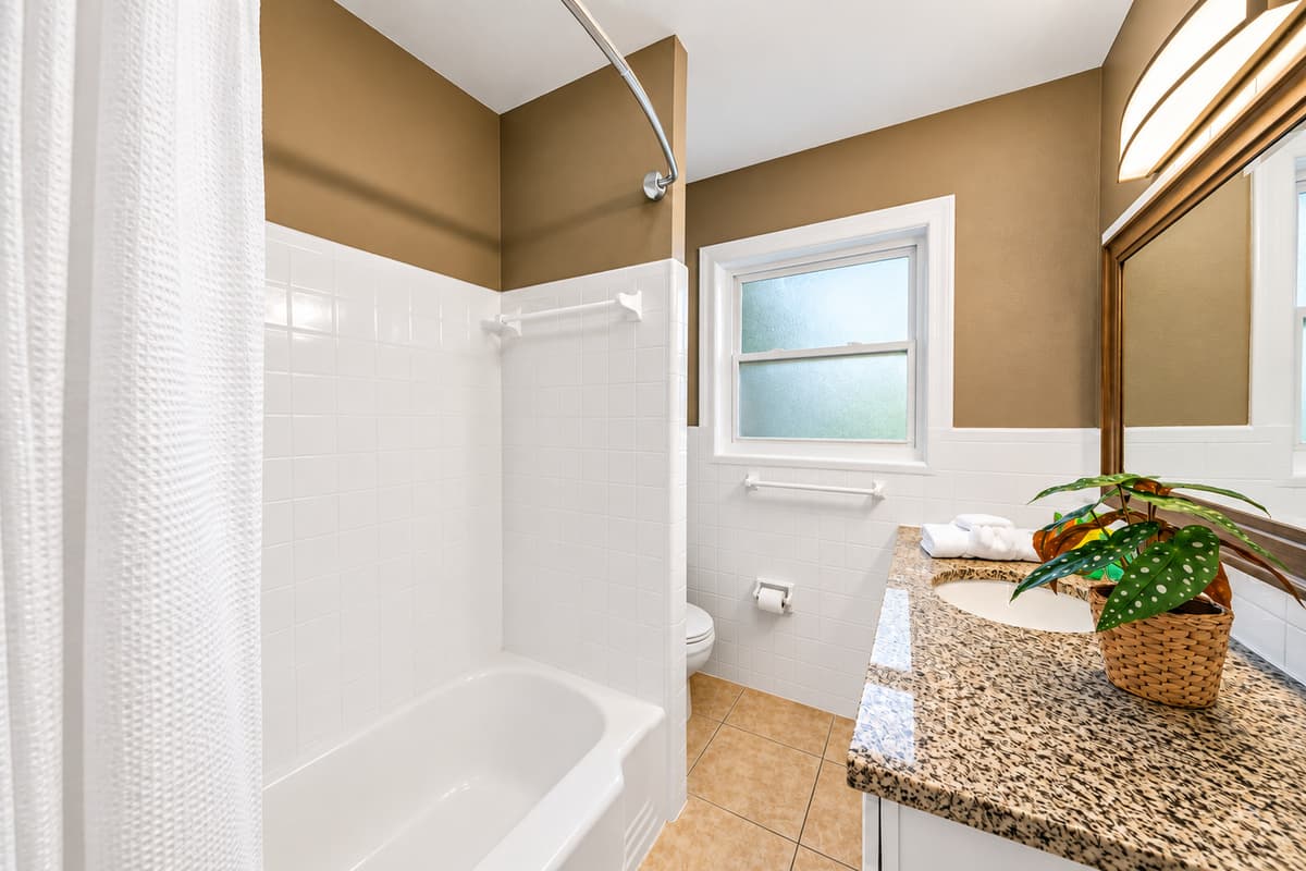 Bright guest bathroom featuring a full bathtub and shower setup with plenty of natural light.