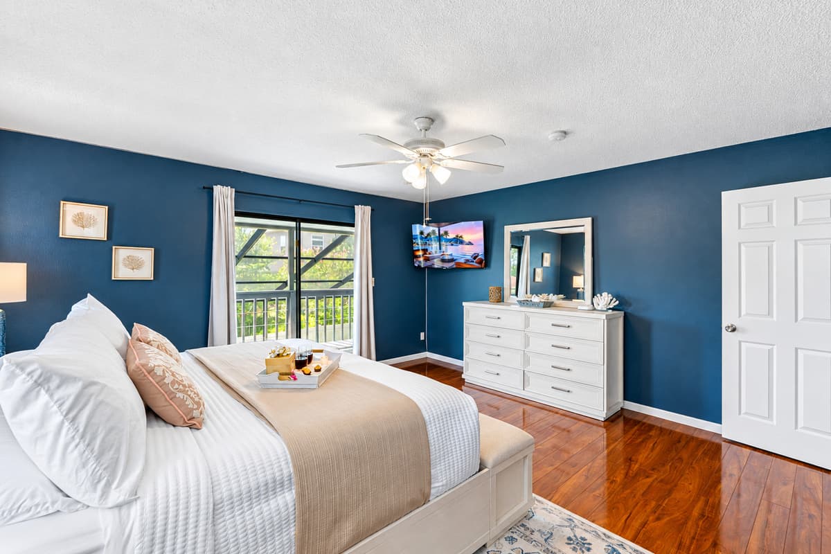 Unwind in this elegant bedroom where deep blue walls and soft lighting create a cozy, tranquil environment perfect for recharging.