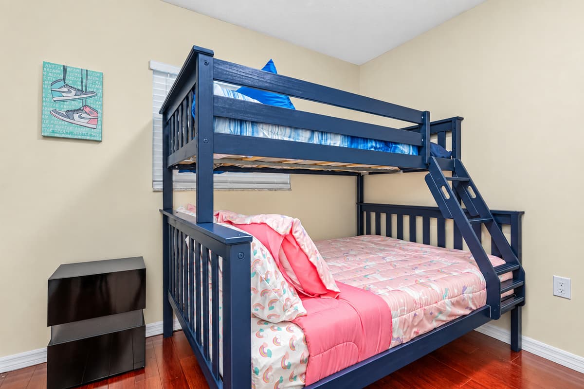 As you enter the room, you're immediately drawn to the twin bed and bunk bed, both dressed in beautiful colored linens and adorned with fluffy pillows.