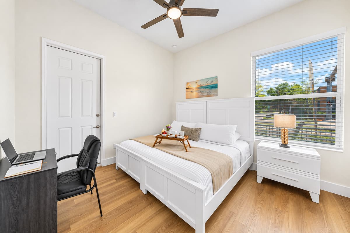 Cozy bedroom with comfortable bed, workspace, and plenty of natural light.