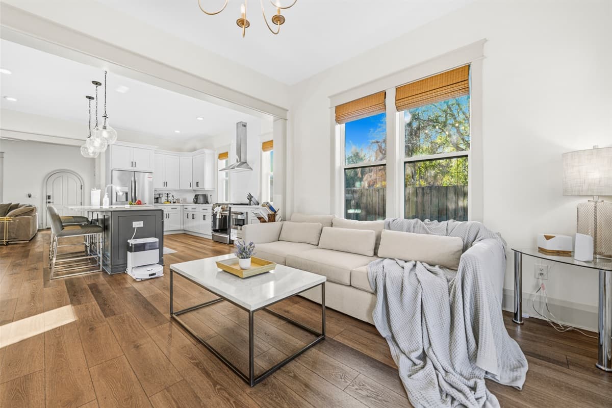 Another sun-soaked view of the versatile sitting room — gold chandelier, plush sofa, and large windows framing the lush Florida greenery. Whether you use it as a lounge, office, or reading nook, this brand-new space delivers.