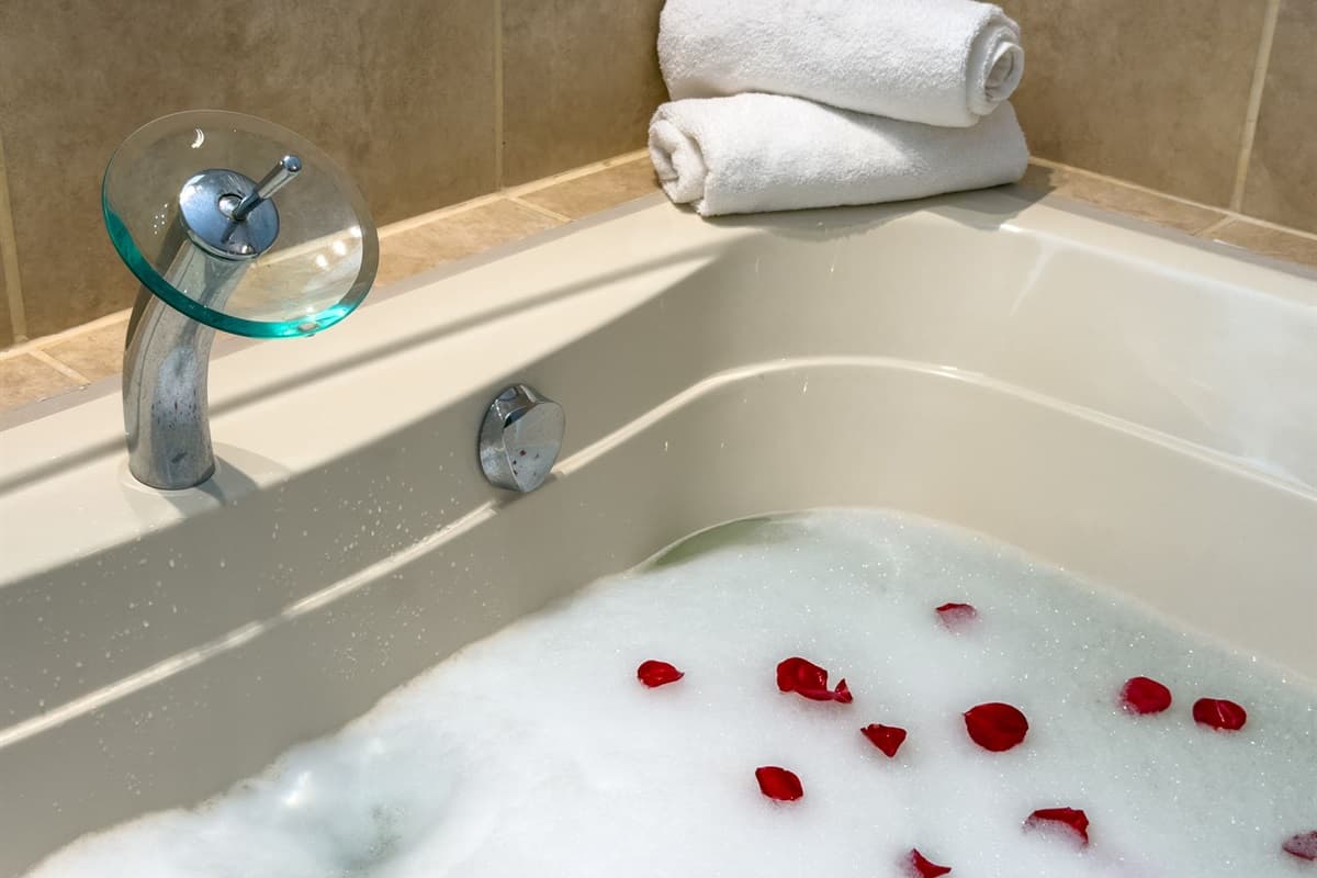 The ensuite bathroom features a double vanity, soaking tub, and warm tile accents.