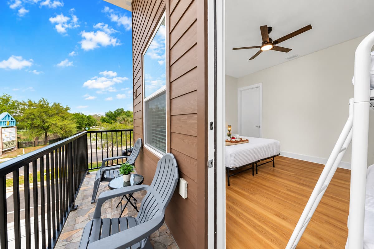 Bedroom 3 opens straight onto the balcony. Step from the bunk-and-king bedroom onto a private balcony with chairs and blue Florida sky. Kids nap inside while you read outside: close enough to hear, far enough to relax.
