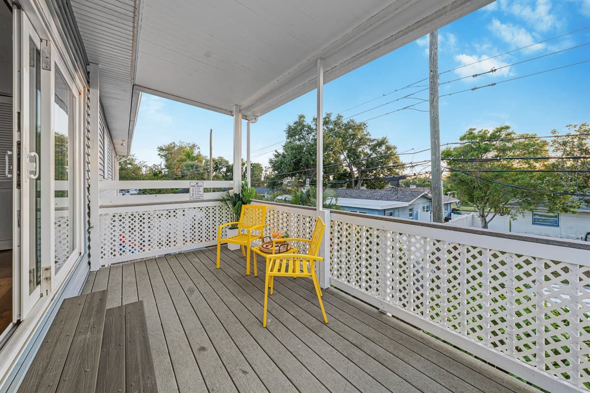 Spacious covered balcony with bright yellow seating—perfect for relaxing outdoors 