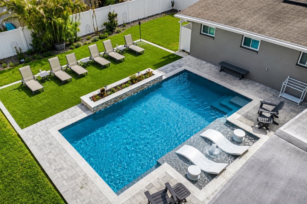 Aerial view of the private backyard oasis highlighting the pool, lounge chairs, and spacious outdoor layout.