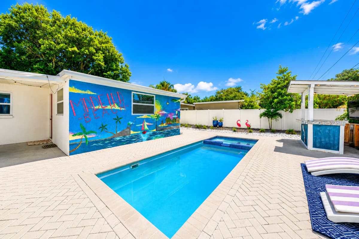 Wide-angle backyard view showcasing the private pool, colorful murals, shaded gathering areas, and outdoor amenities.