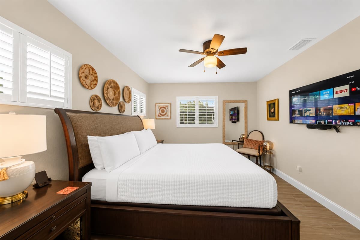 Large king bedroom with stylish décor, wall-mounted TV, and abundant natural light.