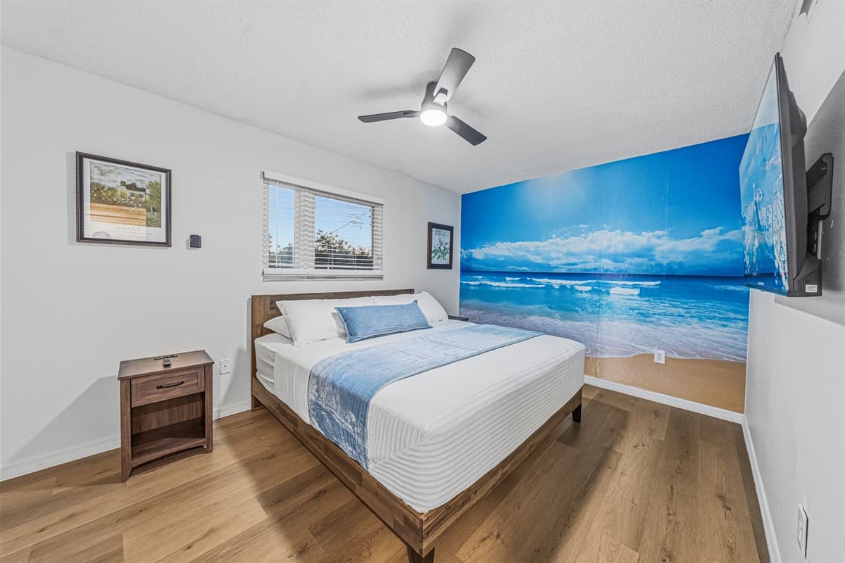 Relaxing bedroom retreat with beach mural and soft tones, perfect for a peaceful getaway 