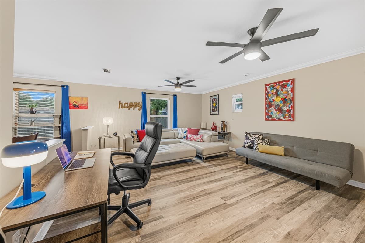 Spacious lounge with workspace setup, large sectional, and bright windows—perfect for both work and relaxation.