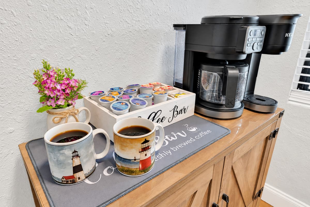 Dual coffee maker: pods for whoever is in a hurry, a full pot for whoever isn't. Mugs, capsules and sugar all on the same little station — the first thing the house uses every single morning of the stay.