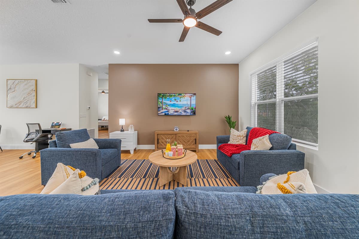 Bright and inviting living room with large windows, cozy seating, and open layout for relaxing.