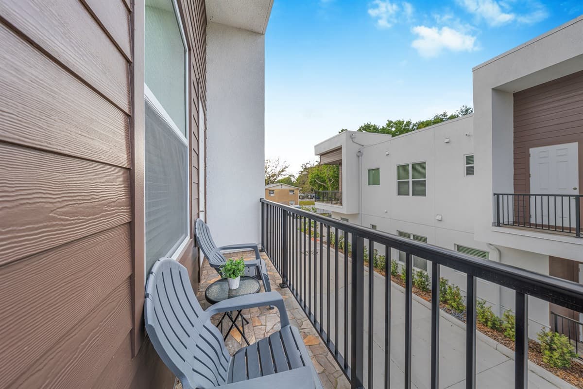 Private balcony with cozy seating, offering a quiet spot to relax and enjoy fresh air with neighborhood views.