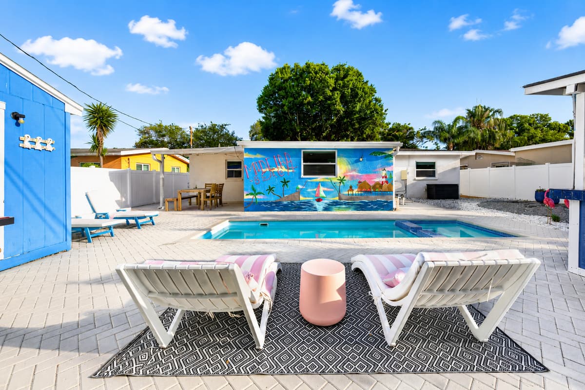 Scenic view from the lounge area overlooking the pool, outdoor dining patio, and colorful mural-adorned exterior wall.