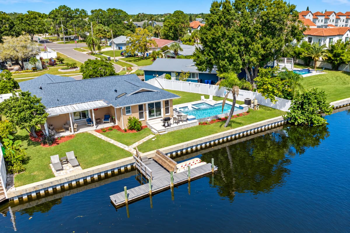 Aerial back view of the property showcasing the immaculate heated pool and access to dock in the lake. Don't hesitate to send us a message!