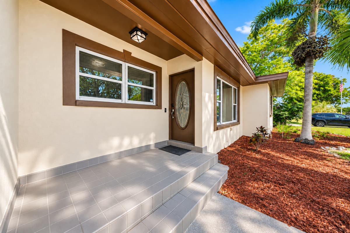 Welcoming front entrance with tropical landscaping and charming curb appeal.