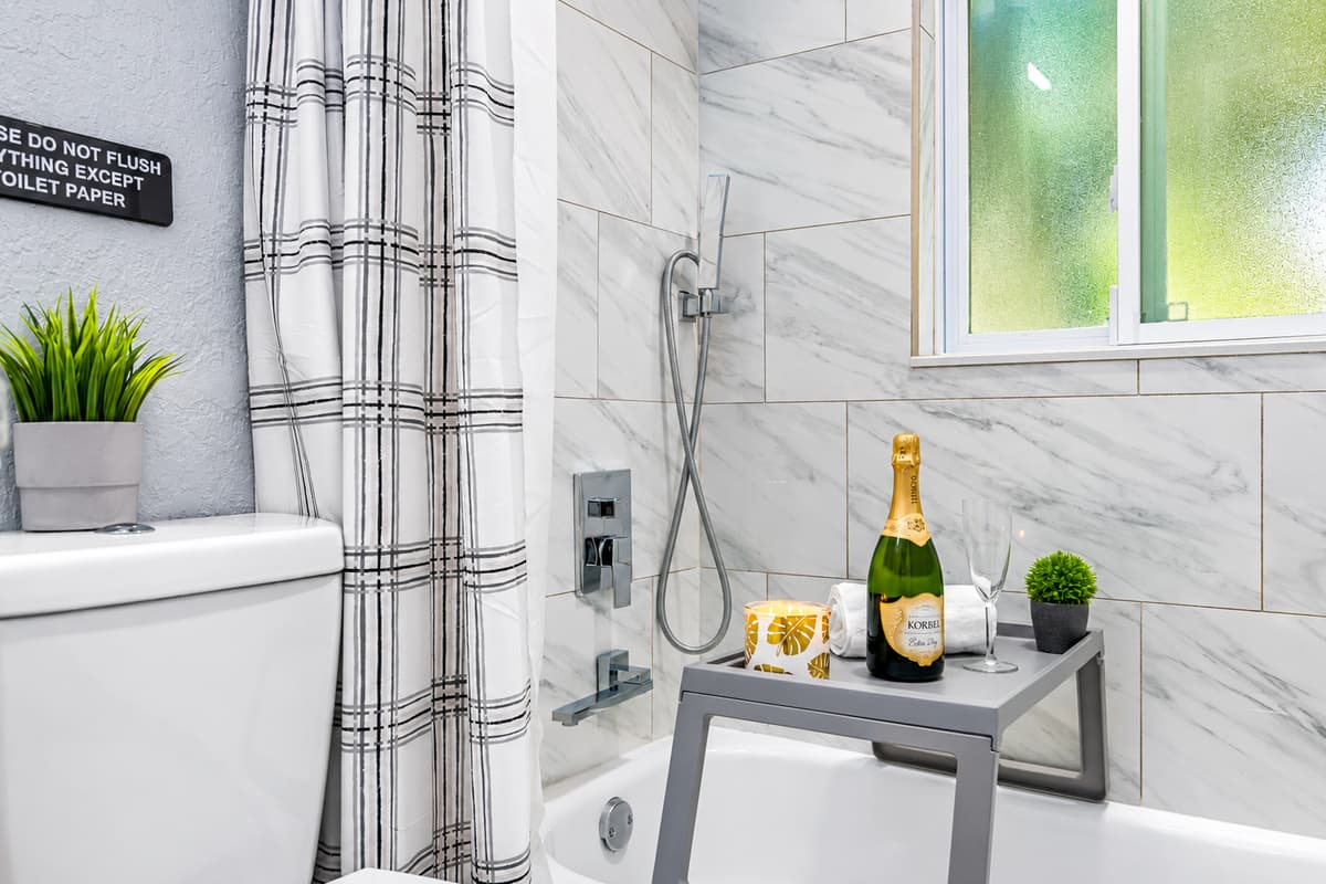 Tub and shower in the king suite bath. A full tub with shower, modern tile, and a handheld showerhead. Perfect for bathing little ones or a relaxing soak. Fresh towels are ready on arrival.