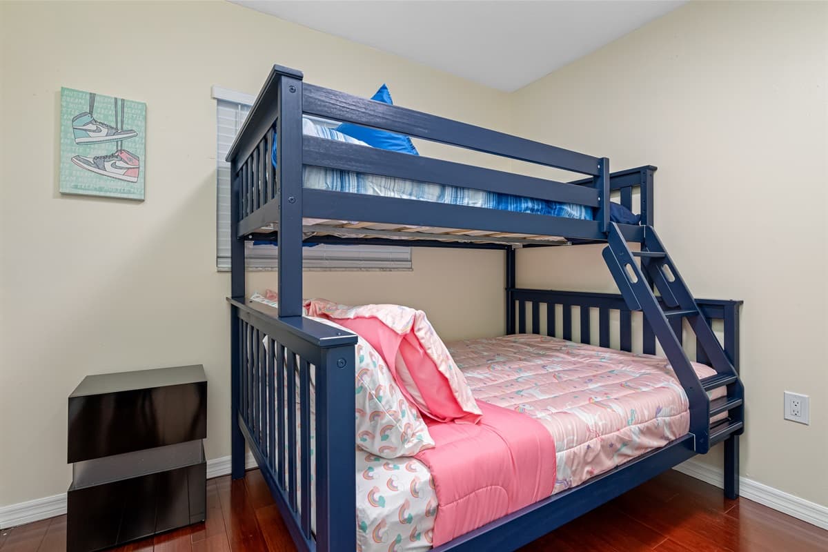 As you enter the room, you're immediately drawn to the twin bed and bunk bed, both dressed in beautiful colored linens and adorned with fluffy pillows.