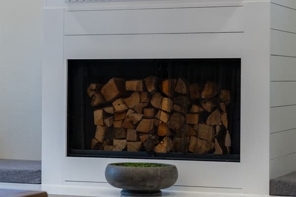 The fireplace’s built-in storage for firewood adds both practicality and a rustic decorative element.