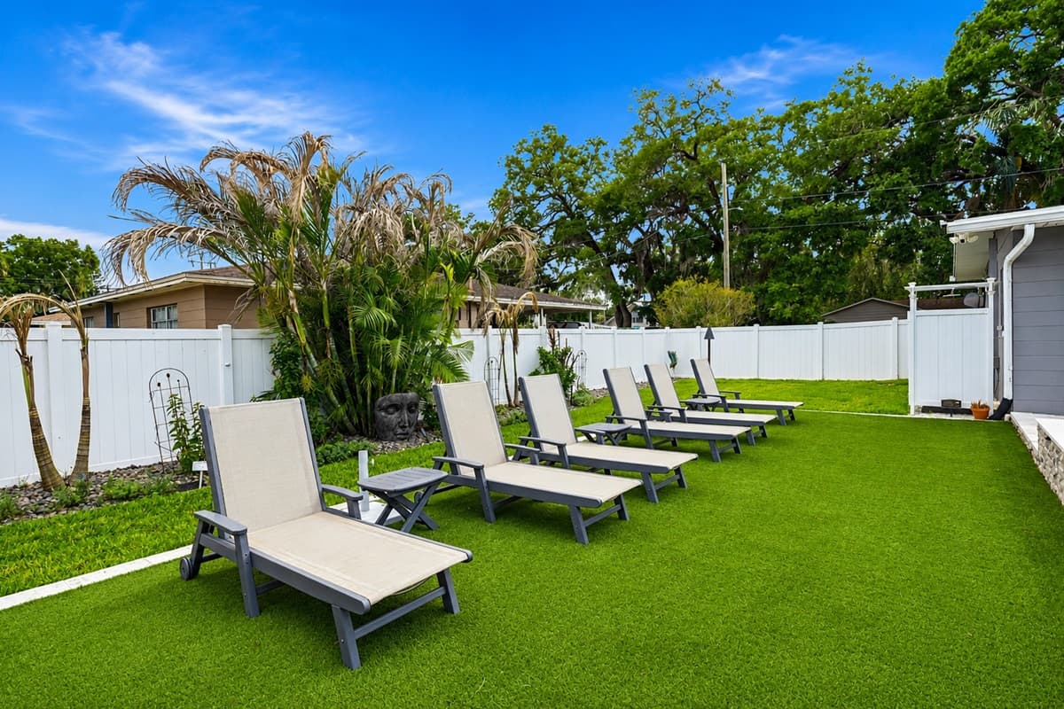 Spacious poolside lounge area with comfortable sun chairs and lush tropical landscaping for the perfect relaxing escape.