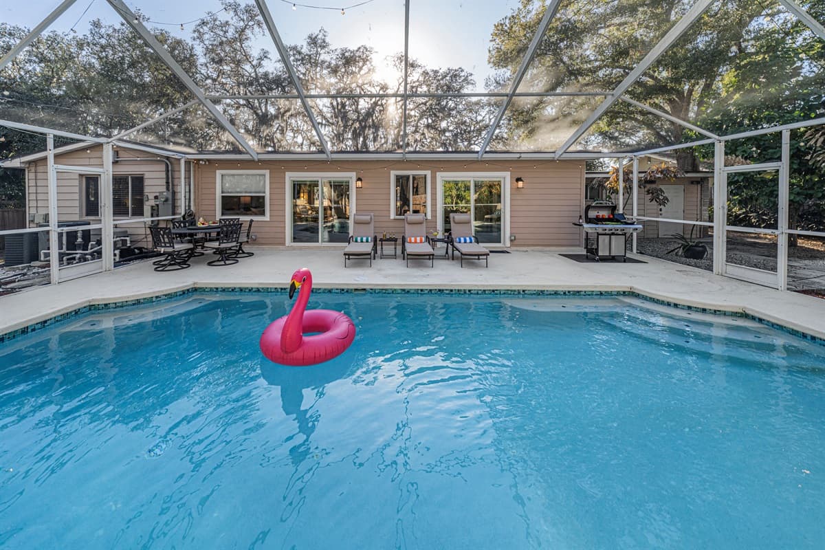A spacious screened-in pool area featuring a sparkling private pool, and patio seating —perfect for soaking up the Florida sunshine.