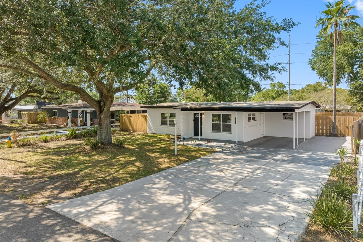 The front yard is adorned with greenery plants, and trees, creating a warm and welcoming atmosphere.