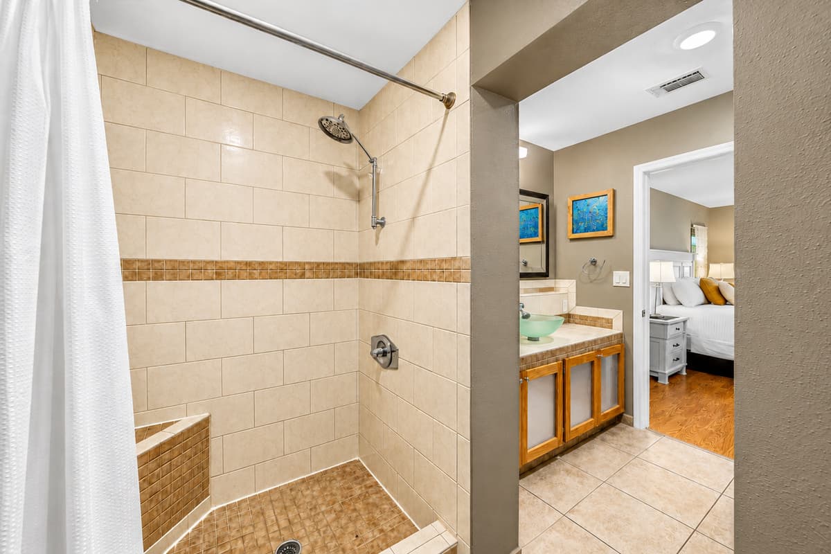 Spacious primary bathroom featuring a large walk-in tiled shower and direct access to the bedroom.