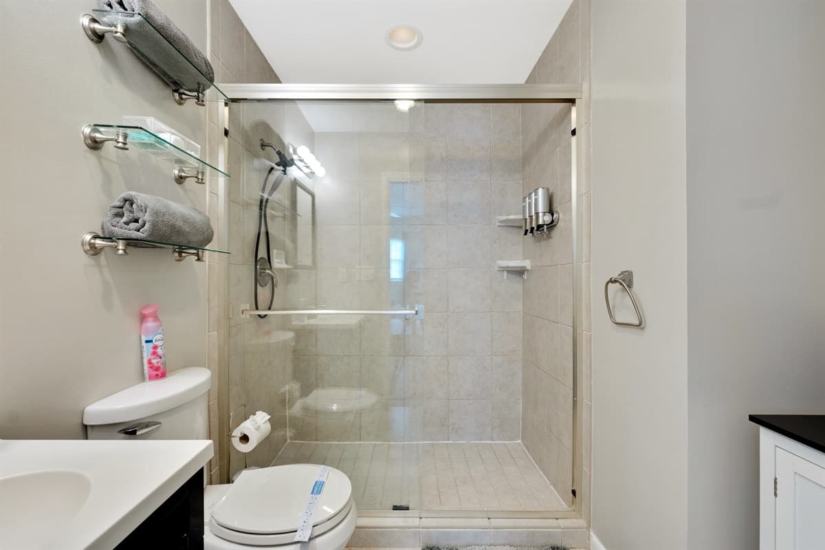The centerpiece of the bathroom is a stunning glass-enclosed shower, offering a sleek and modern aesthetic.