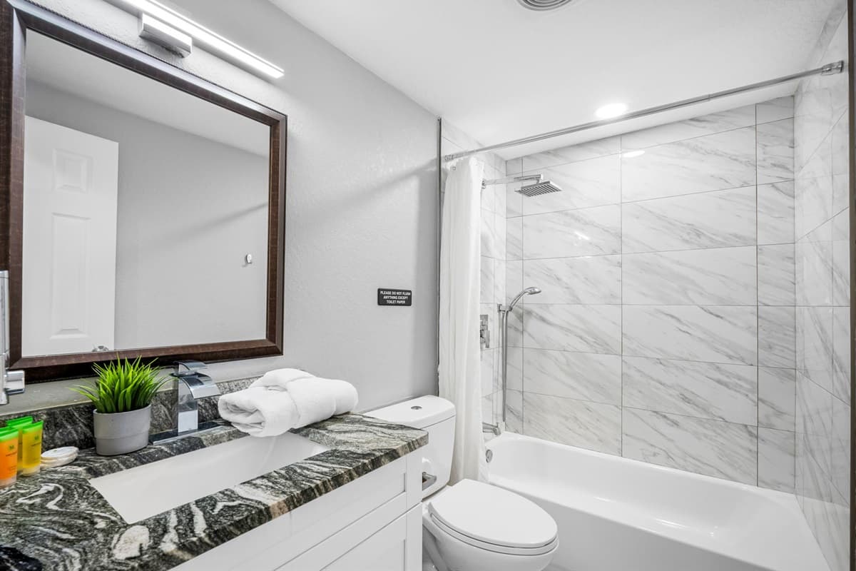 A beautifully designed bathroom featuring marble-style tile, sleek fixtures, and a spacious vanity.