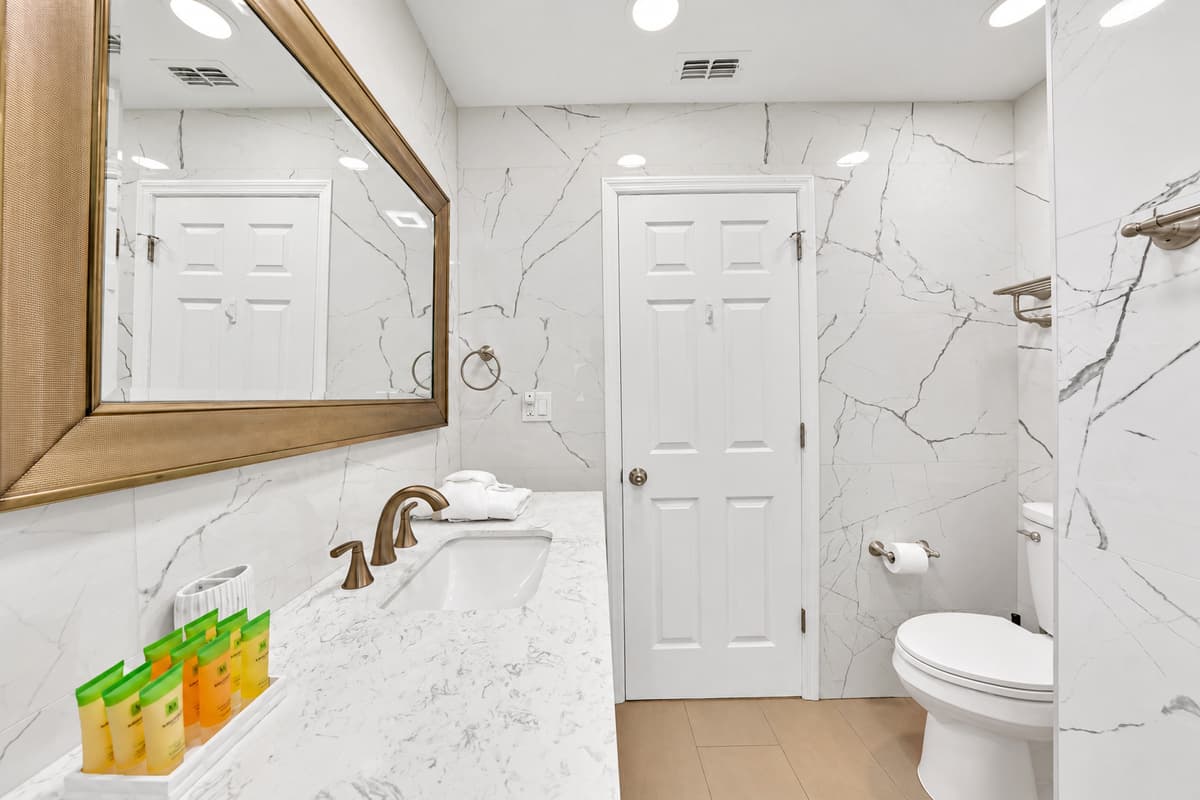 Marble from floor to ceiling, a wide mirror and counter space that doesn't disappear the moment three people share a bathroom. Nine guests, two full baths — and this one is steps from the double-and-twin room, which is exactly where it's needed.