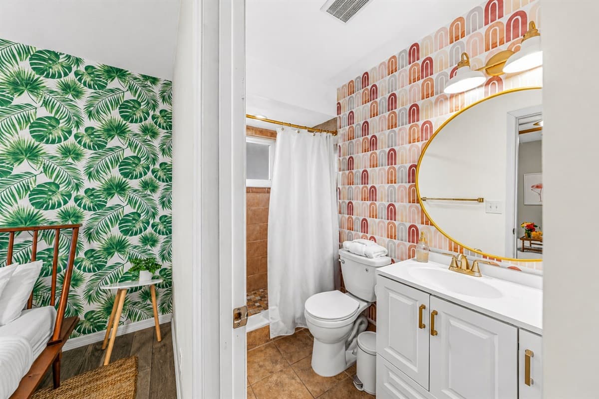 Bright bathroom with a walk-in shower and bold designer wallpaper—blending comfort with unique character.