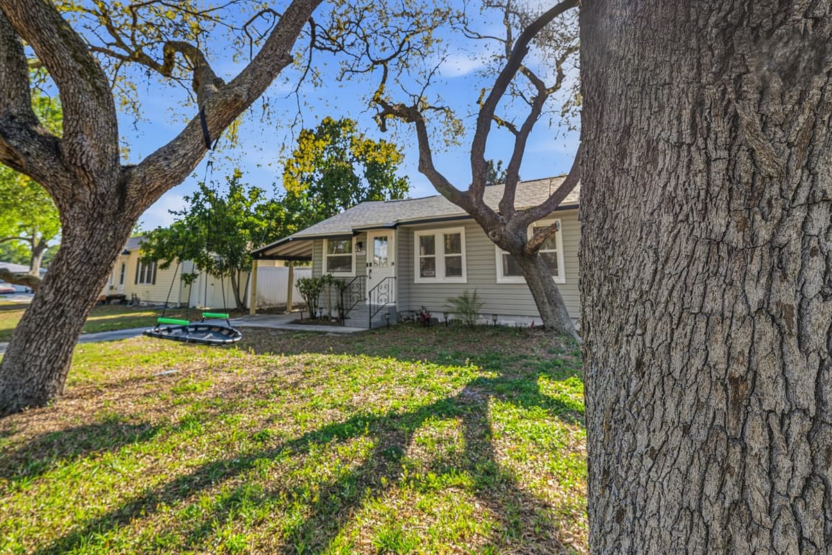 Large front yard with mature trees and shaded lawn.