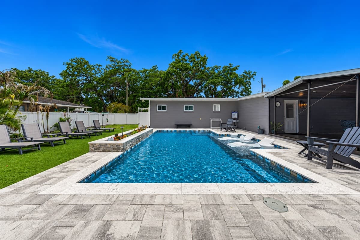 Spacious backyard oasis featuring a large private pool, tanning ledge, and screened outdoor entertaining area.