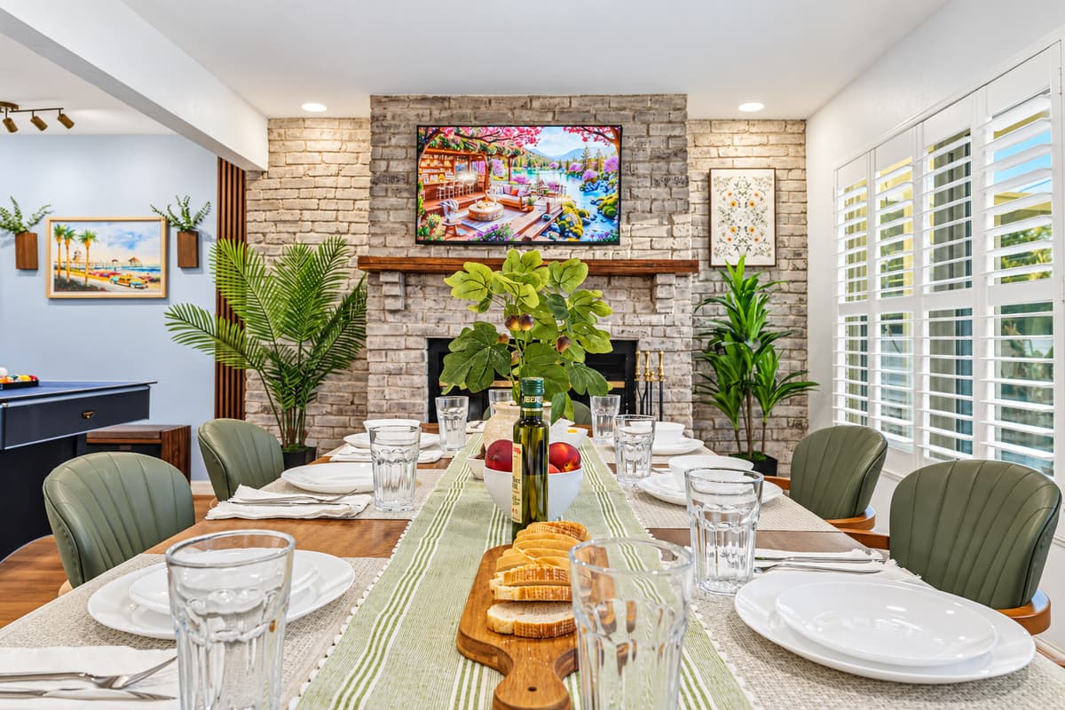 Dining table set near the fireplace, offering a warm and inviting atmosphere for group meals 
Table settings and food are for staging purposes only and are not included.