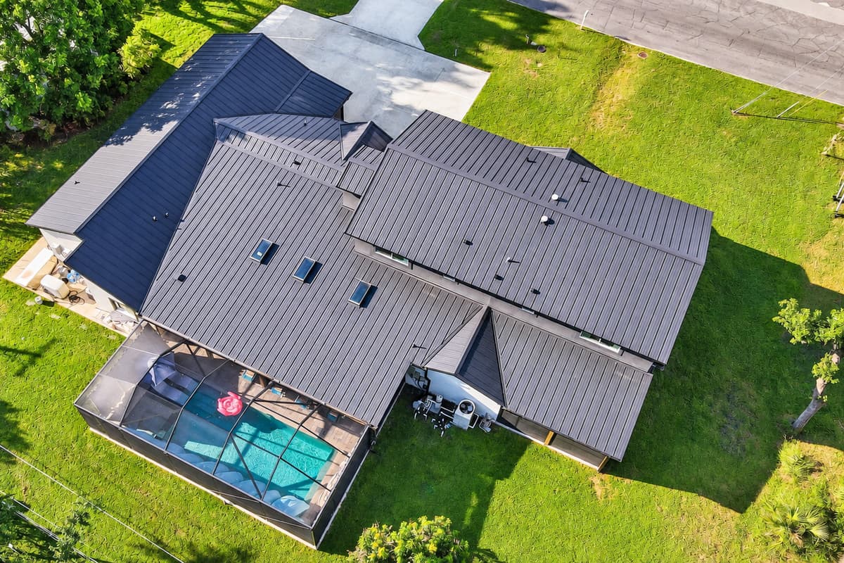 That screened pool is entirely yours for the week. Seen from above: the enclosure, the lanai, the lawn and 4,025 square feet of house wrapped around all of it.