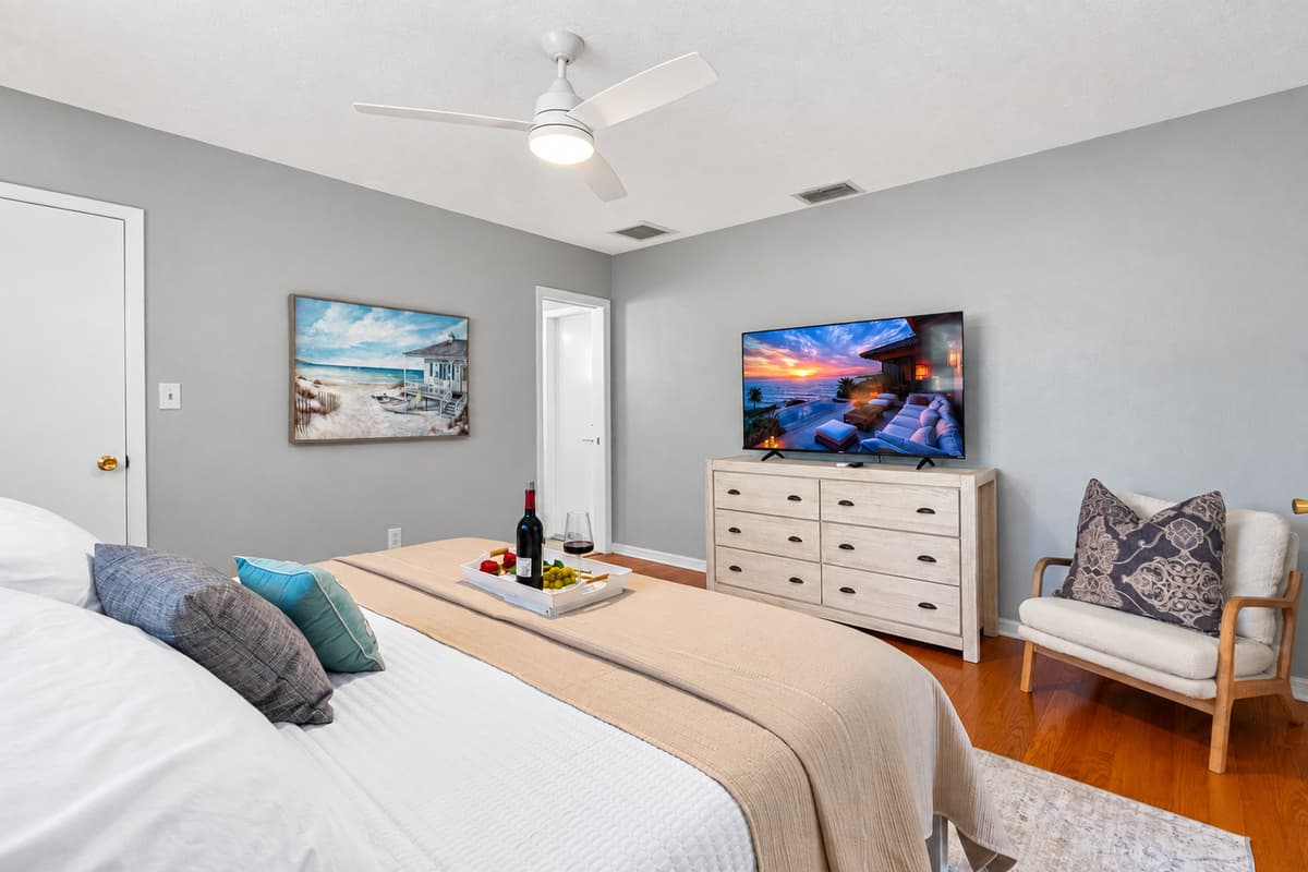 Sleep like royalty in this spacious master bedroom with hardwood floors, warm lighting, and a cozy ambiance.