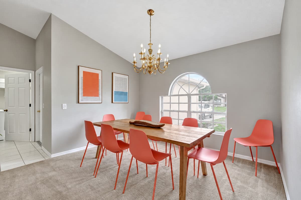 Above the table, a stunning chandelier hangs majestically, casting a soft glow that adds a touch of glamour to the space.