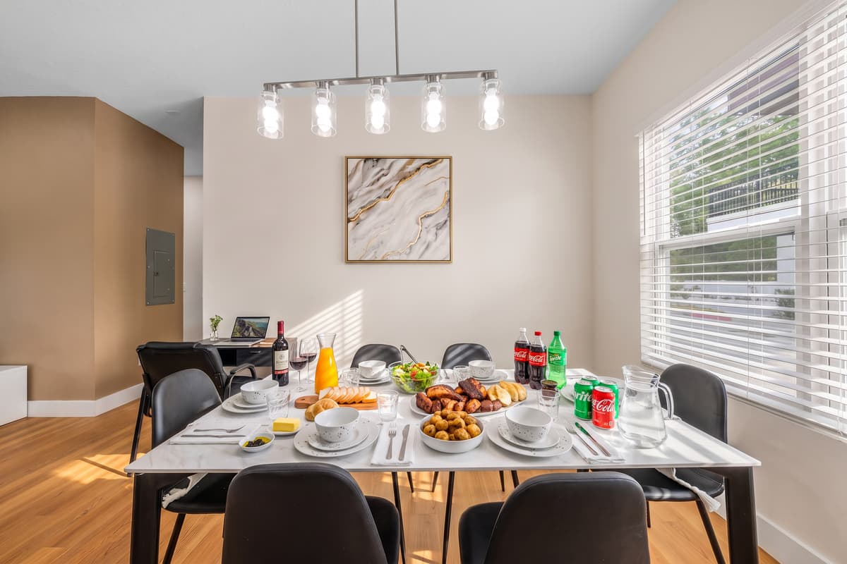 Dinner at home, done properly: a full table, plates and glassware provided, and afternoon light through the blinds