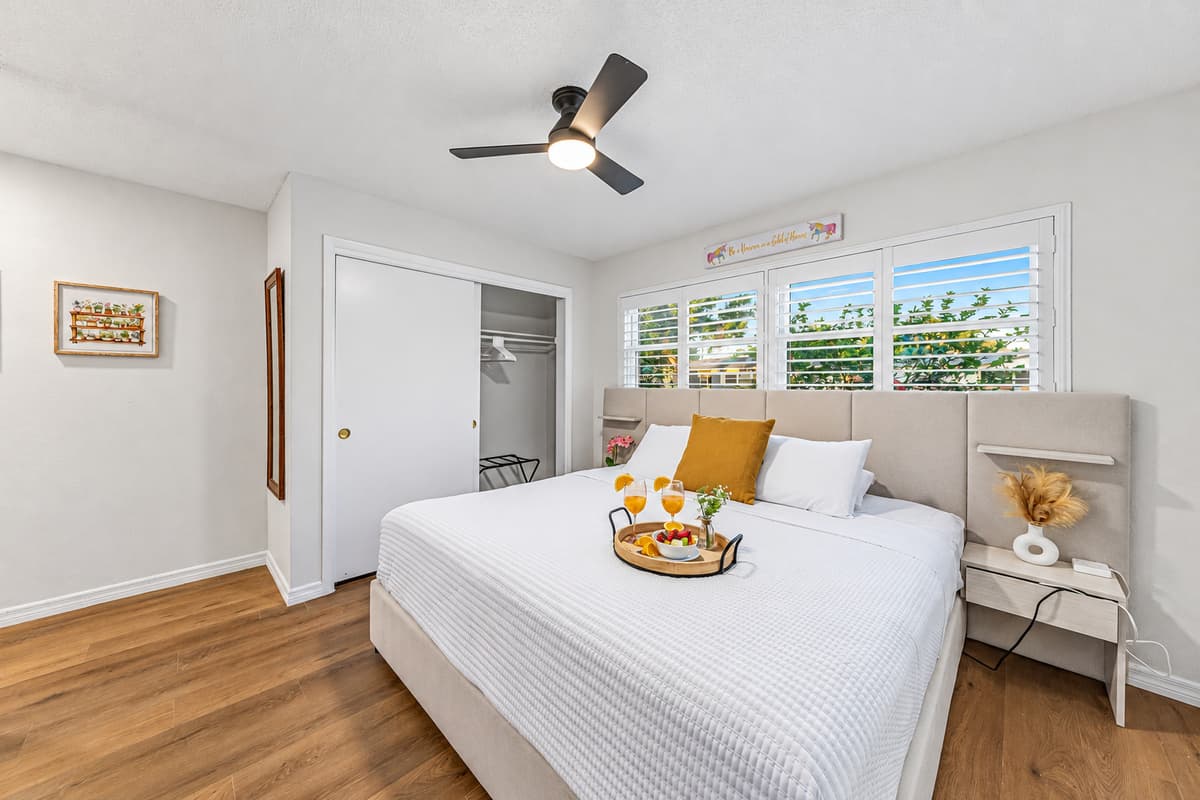 Bright and inviting king bedroom with clean design, natural light, and a relaxing atmosphere 
Tray and food setup shown are for staging purposes only and are not included.
