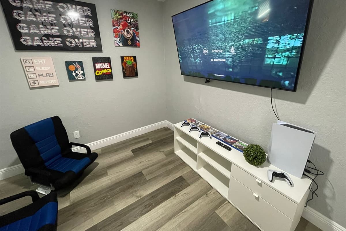 Surrounding the TV, a collection of comfortable and ergonomic chairs awaits, providing the perfect seating for extended gaming sessions.