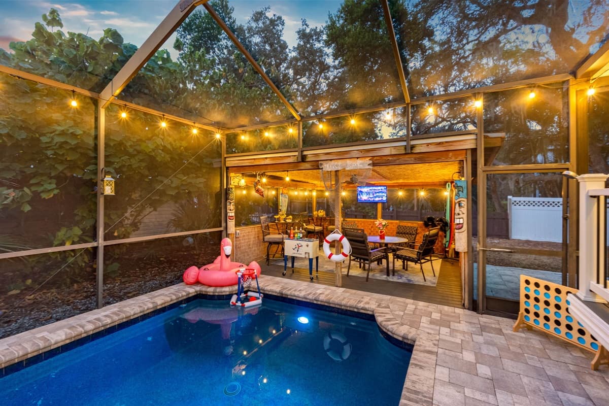 A beautifully lit pool creates the perfect evening ambiance, with cozy seating and a festive outdoor bar just steps away.