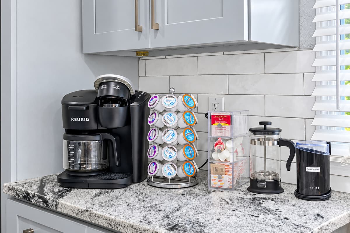 Your coffee bar, ready every morning. A Keurig, K-cup carousel, French press, kettle, and grinder on the granite counter. Brew your favorite before heading to the beach, no drive-thru needed.