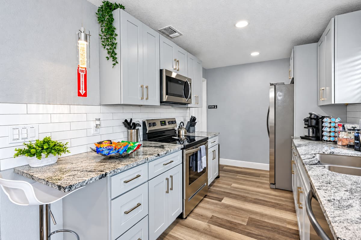 A kitchen ready for real family meals. Granite counters, white shaker cabinets, stainless range, microwave, and dishwasher. Spices, pantry basics, pots, pans, and baking sheets are stocked, so you just bring the groceries.