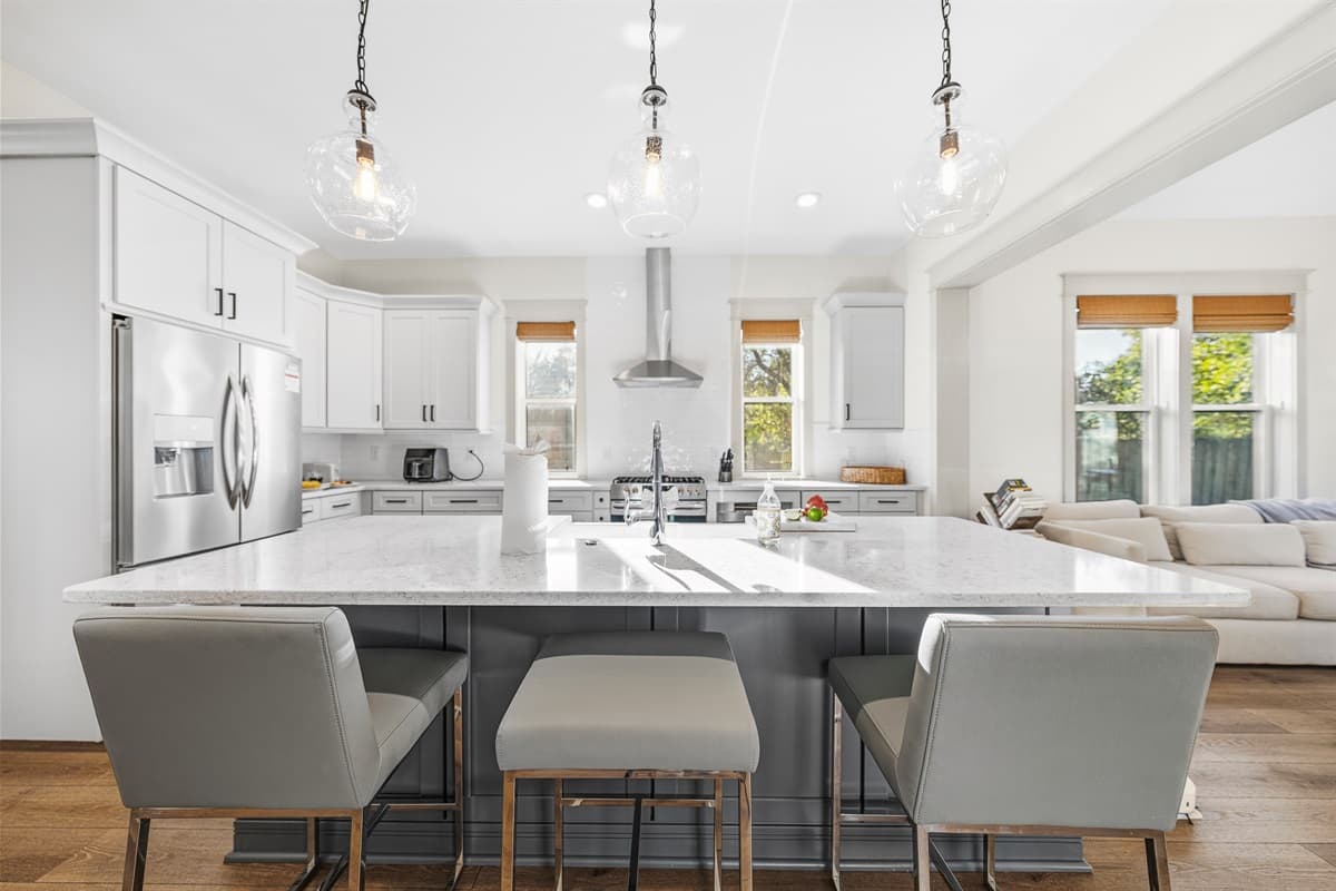 Another stunning angle of the all-new kitchen — bright, open, and flooded with natural light. White quartz counters, modern pendant lights, a generous island with seating, and a full dining area make this the heart of the home.