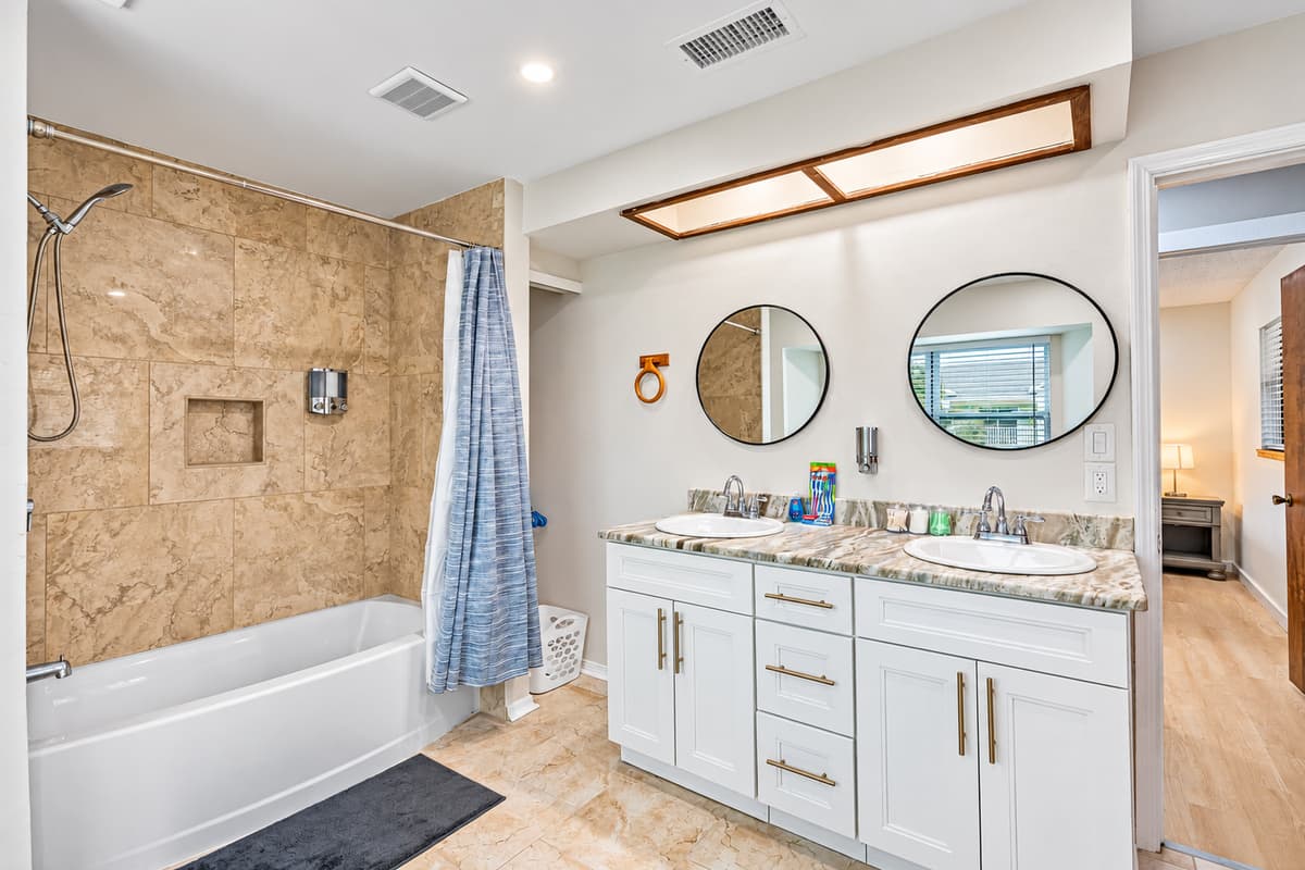 Indulge in the ultimate comfort and luxury of our exquisite bathroom, complete with a delightful combination of a tub and shower, elegant his and her sinks, and a modern toilet.