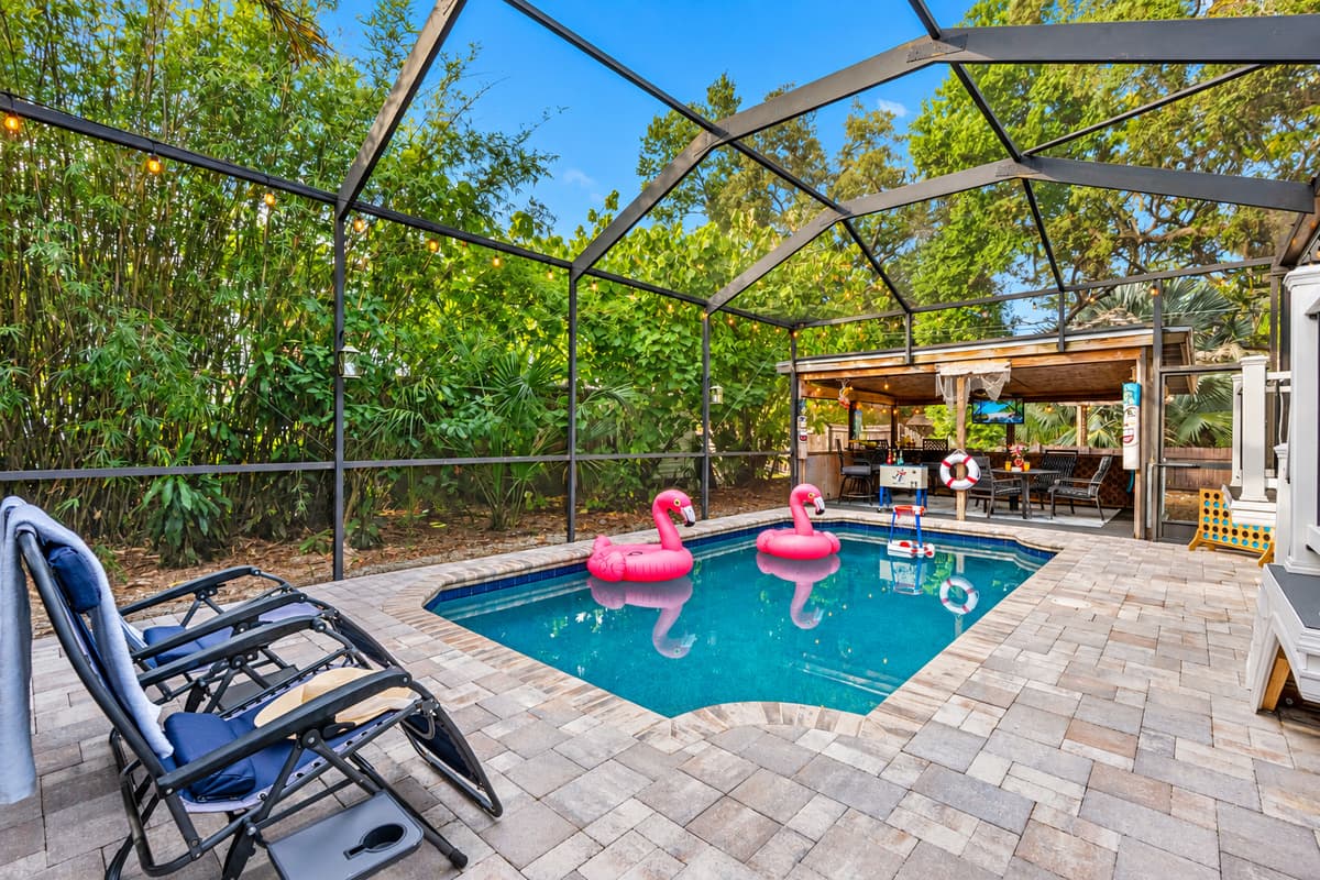 Enjoy this inviting pool oasis featuring comfortable lounge chairs, fun flamingo floats, and a fully screened enclosure for year-round comfort.