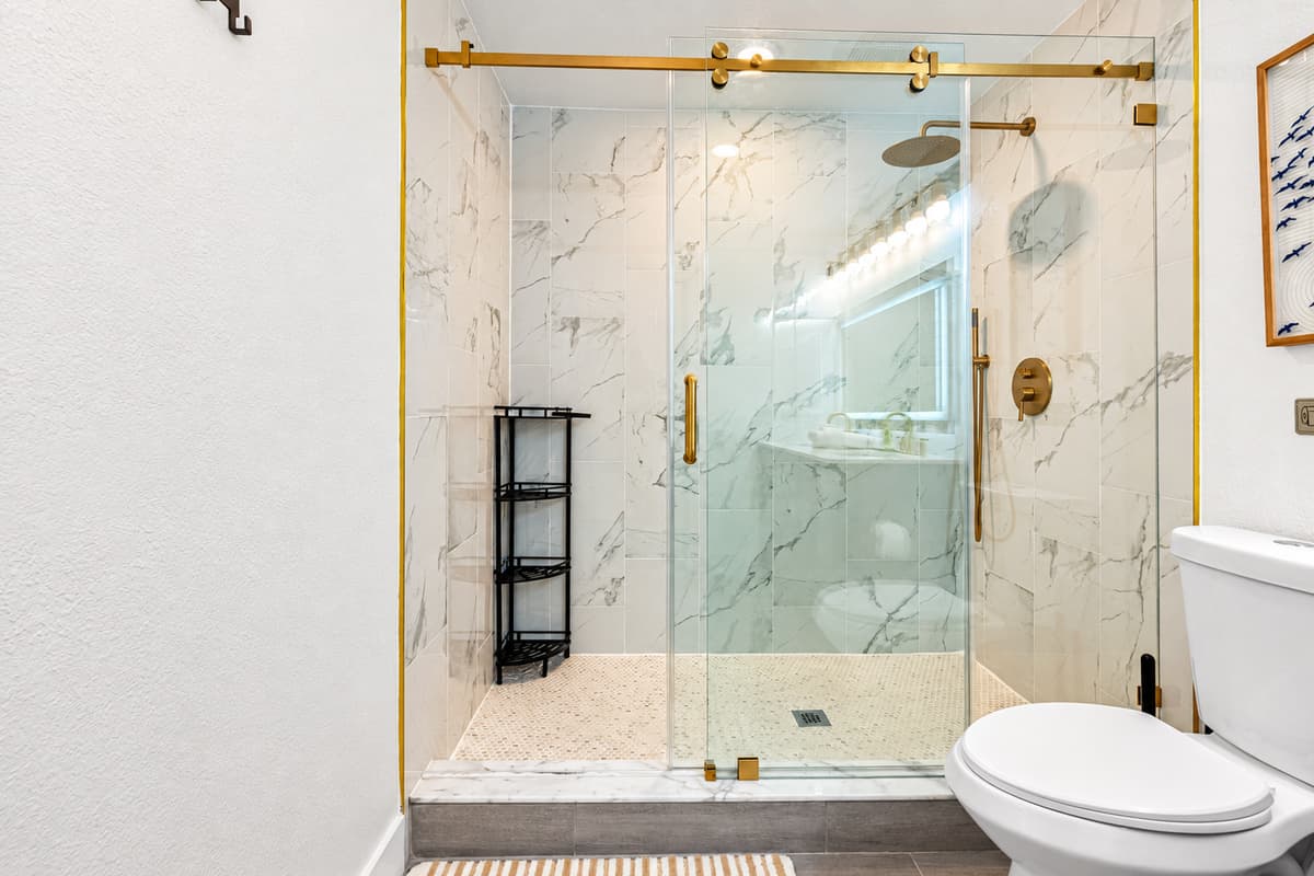 Bedroom 1 - Ensuite: This elegant bathroom includes a backlit mirror, luxe gold accents, and a spacious shower perfect for unwinding.