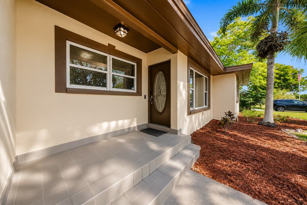 Welcoming front entrance with tropical landscaping and charming curb appeal.