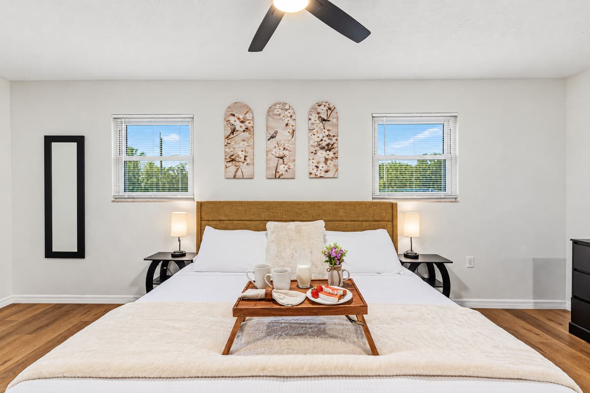 Elegant king bedroom with symmetrical design, soft lighting, and a peaceful atmosphere 
Tray and food setup shown are for staging purposes only and are not included.
