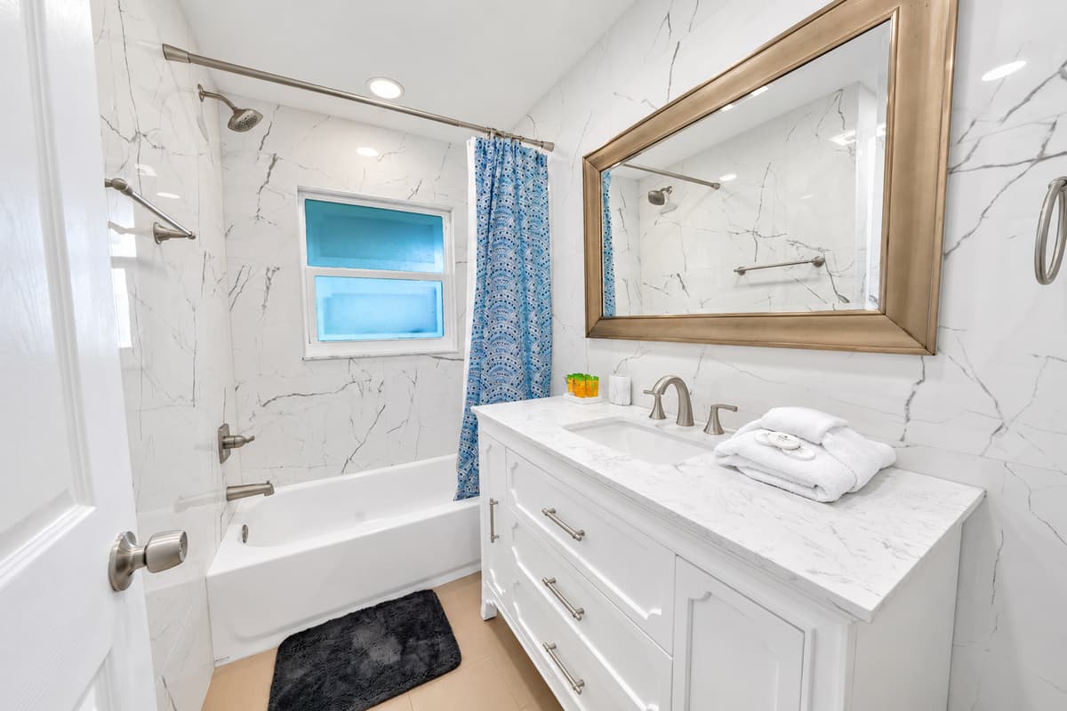 The tub/shower combo is the one that matters after a beach day — kids rinsed off in five minutes, sand down the drain, nobody waiting in line. Marble-top vanity, wide mirror, fresh towels already folded when you walk in.